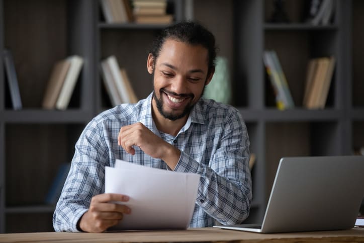 A man at a desk smiling and reviewing a college application