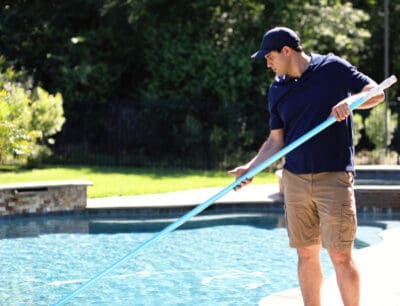 A man using a net to clean a pool